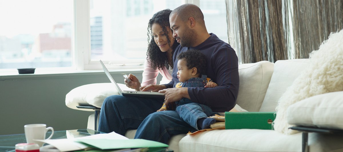 couple on sofa with kid checking laptop
